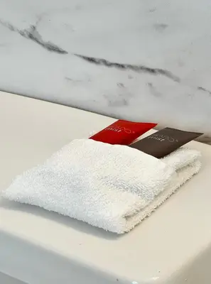 a white towel on a table with a book at South of Fifth Ocean Drive Apt in Miami Beach