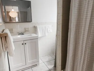 a white bathroom with a sink and a mirror at Lovely Bohemian Apartment in Fort Lauderdale