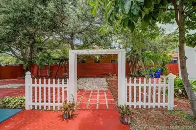 a white gate leading to a garden with a red pathway at Cute Private Room - Close to airport & Free parking 01 in Miami