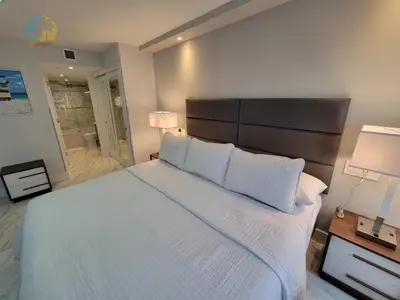 a bedroom with a large bed with white sheets and pillows at Deluxe Beach Resort - HORA RENTALS in Miami Beach