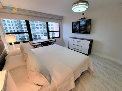 a bedroom with a large white bed and a desk at Deluxe Beach Resort - HORA RENTALS in Miami Beach