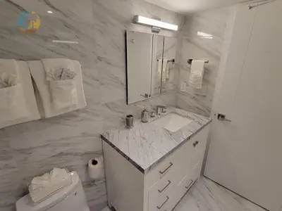 a white bathroom with a sink and a toilet at Deluxe Beach Resort - HORA RENTALS in Miami Beach