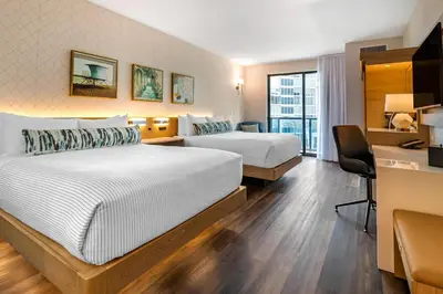 a hotel room with two beds and a desk at Cambria Hotel Fort Lauderdale Beach in Fort Lauderdale