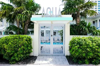 a white gate in front of a building with palm trees at Aqua Hotel in Fort Lauderdale