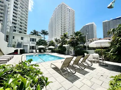 a pool with chairs and umbrellas and buildings at Aqua Hotel in Fort Lauderdale