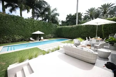 a backyard with a swimming pool with chairs and an umbrella at Villa Naomi - Luxury Design New Home in Miami