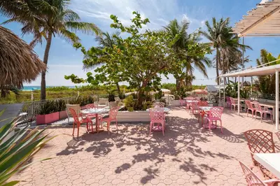 a patio with tables and chairs and the ocean at The Savoy Hotel & Beach Club in Miami Beach