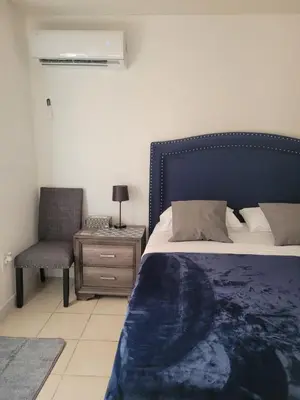 a bedroom with a bed with a blue headboard and a chair at Welcome Heart and Reliable Heart Vacation Houses in Miami