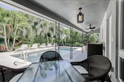 a patio with a table and chairs and a swimming pool at Designer Delight in Fort Lauderdale