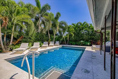 a swimming pool with lounge chairs and palm trees at Designer Delight in Fort Lauderdale