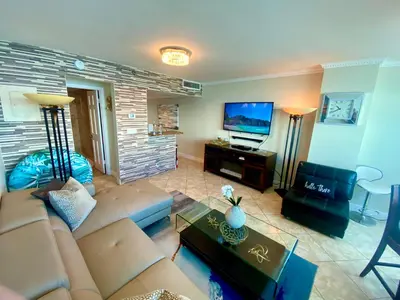 a living room with a couch and a flat screen tv at Large luxurious direct ocean front Penthouse or Deluxe 1 BR ocean front condo-Beach access- Free parking- Remodeled in Miami Beach
