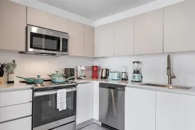 a kitchen with white cabinets and stainless steel appliances at Lofts of Aventura in Miami