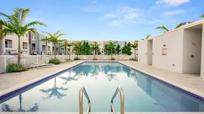 a swimming pool with two chairs in front of a building at Lofts of Aventura in Miami