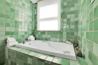 a green tiled bathroom with a tub and a window at NEW Amazing large 3BR direct oceanfront Penthouse On Ocean Drive!! in Miami Beach