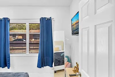 a bedroom with blue curtains and a window at Boutique One Bdrm Close To Aventura Mall & Beach in Hallandale Beach
