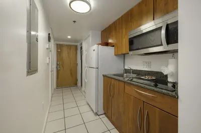 a kitchen with wooden cabinets and a white refrigerator at Studios in Brickell with Pool, Gym, free parking and Game Room in Miami