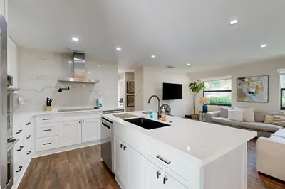 a white kitchen with a sink and a living room at Mid-Century Modern Oasis in Miami