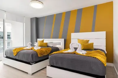 two beds in a bedroom with yellow and gray walls at Luxury 1BD Apt in Downtown Brickell free parking in Miami