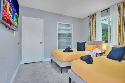 a bedroom with two beds and a flat screen tv at Escape GameRoom, BAR, BBQ, Spacious,KING Bed, All Luxury mattresses, Near Beach, 6 blocks away from Bars, Nite Clubs, Res, Shops in Miami