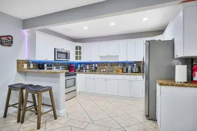 a kitchen with white cabinets and two bar stools at Escape GameRoom, BAR, BBQ, Spacious,KING Bed, All Luxury mattresses, Near Beach, 6 blocks away from Bars, Nite Clubs, Res, Shops in Miami