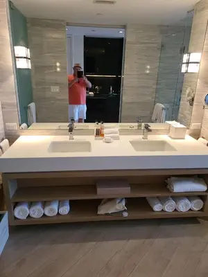 a man taking a picture of a bathroom sink at Residences Suite South Beach in Miami Beach