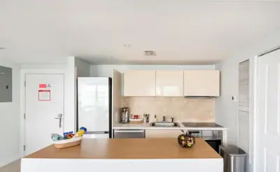 a kitchen with white cabinets and a wooden counter top at The Carlyle Oceanfront Luxe Condo Miami Beach in Miami Beach
