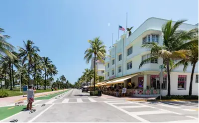a person riding a skateboard down a street in front of a building at The Carlyle Oceanfront Luxe Condo Miami Beach in Miami Beach