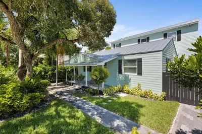 a green house with a tree in the yard at Las Olas Villa with HEATED Salt Water Pool in Fort Lauderdale