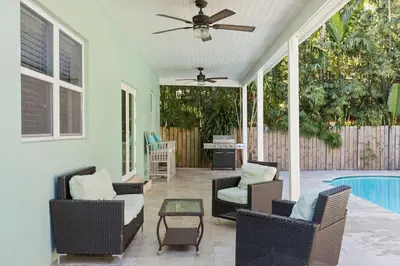 a screened in porch with chairs and a ceiling fan at Las Olas Villa with HEATED Salt Water Pool in Fort Lauderdale