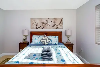 a bedroom with a bed with blue and white sheets and pillows at Las Olas Villa with HEATED Salt Water Pool in Fort Lauderdale