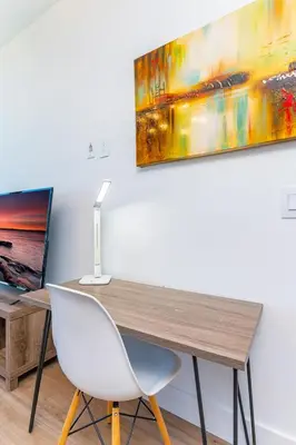 a desk with a white chair and a painting on the wall at Global Luxury Suites Miami Worldcenter in Miami