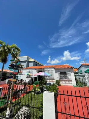 a fence in front of a building with a palm tree at Habitacion Centrica Calle 8 Miami (2) in Miami