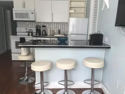 a kitchen with three bar stools and a counter at Sun Sand and Love - Lovely 2 Beds, 2 Bath Condo in Miami Beach