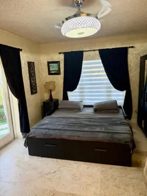 a bedroom with a bed with blue curtains and a window at Homestay Weston Ranches in Southwest Ranches
