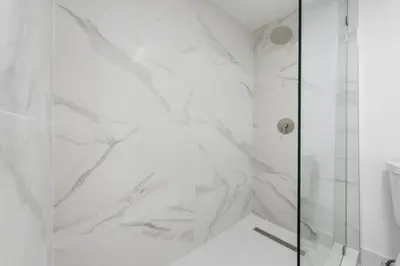 a shower with white marble walls and a glass door at SOBE suites in Miami Beach in Miami Beach