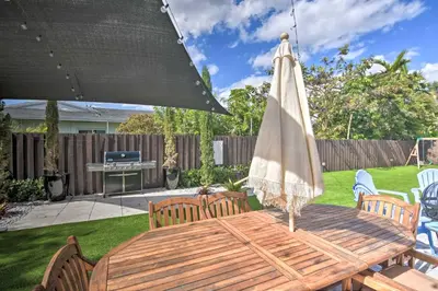 a wooden table with a patio umbrella and chairs at Miami Home Outdoor Pool with Slide and Fire Pit! in Kendall