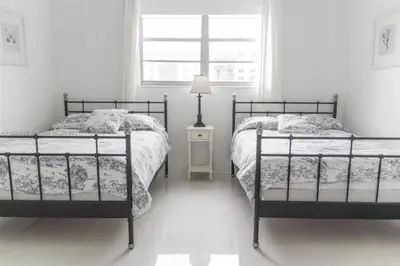 two beds in a white bedroom with a window at DISFRUTA SUNNY ISLES OCEAn 1206 STR-02816 in Miami Beach