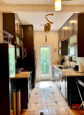 a kitchen with black cabinets and a door with a window at Entire private Beautiful 2 Bedroom plus Den House with gated front&back yard and Free parking 10min drive to Miami Beach in Miami