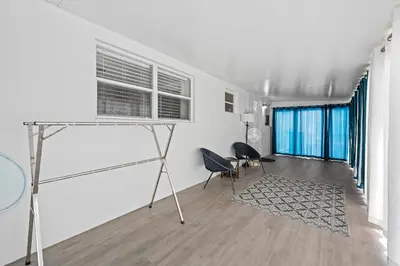 a living room with white walls and a table and chairs at Comfy BNB w/ King Bed + Work/Travel + Beach 8 Min in Hallandale Beach