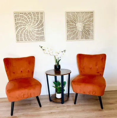 two orange chairs and a table with a vase of flowers at Enchanting cozy Apartment 10 min away from airport, Calle 8, Brickell, Coral Gables, the beach and more! in Miami