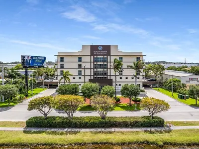 an office building with trees in front of it at South River Suites in Medley