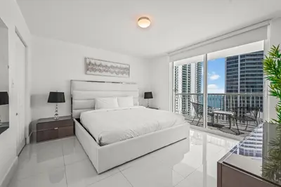 a white bedroom with a bed and a balcony at Luxurious Condo with PARKING in Brickell Miami in Miami