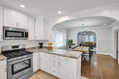a kitchen with white cabinets and a dining room with a table at Beach House w/ Heated Pool in Hollywood