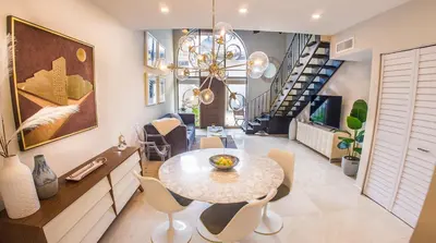 a dining room with a table and chairs and a staircase at Villas at St James Place UNIT F, Luxury, Pet Friendly in Miami