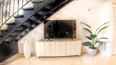 a living room with a tv and a staircase at Villas at St James Place UNIT F, Luxury, Pet Friendly in Miami