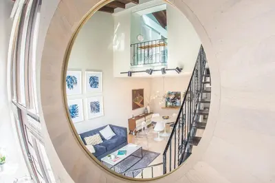 a round mirror in a living room with a blue couch at Villas at St James Place UNIT F, Luxury, Pet Friendly in Miami