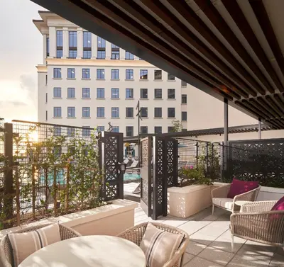 a balcony with tables and chairs and a building at Loews Coral Gables Hotel in Miami