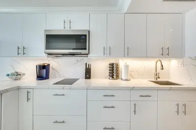 a white kitchen with white cabinets and a microwave at Sunny Isles Beach Retreat with Resort Perks! in Miami Beach