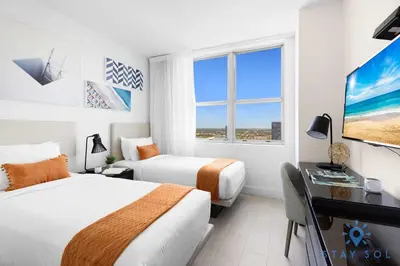 a hotel room with two beds and a desk and a tv at Luxury 3 Br - Corner Balcony - Panoramic View - Pools in Hollywood