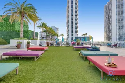 a row of chaise lounges on a lawn with palm trees at Wrap Around Balcony, Paradise Beach & Amazing Pools in Hollywood